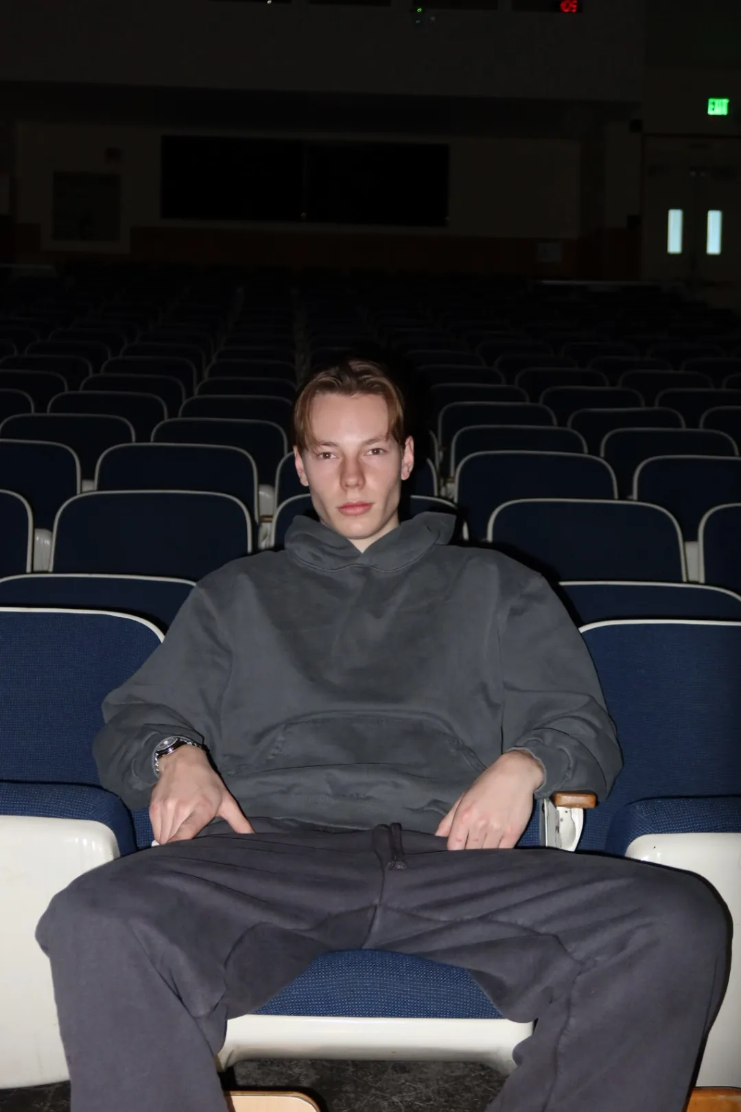 Student in a blank grey hoodie and matching sweatpants seated in a lecture hall