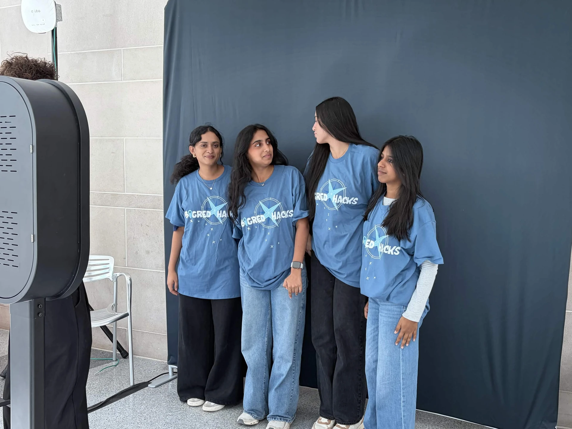 Four Cornell BigRed//Hacks participants wearing blue compass graphic tees at the event photo booth