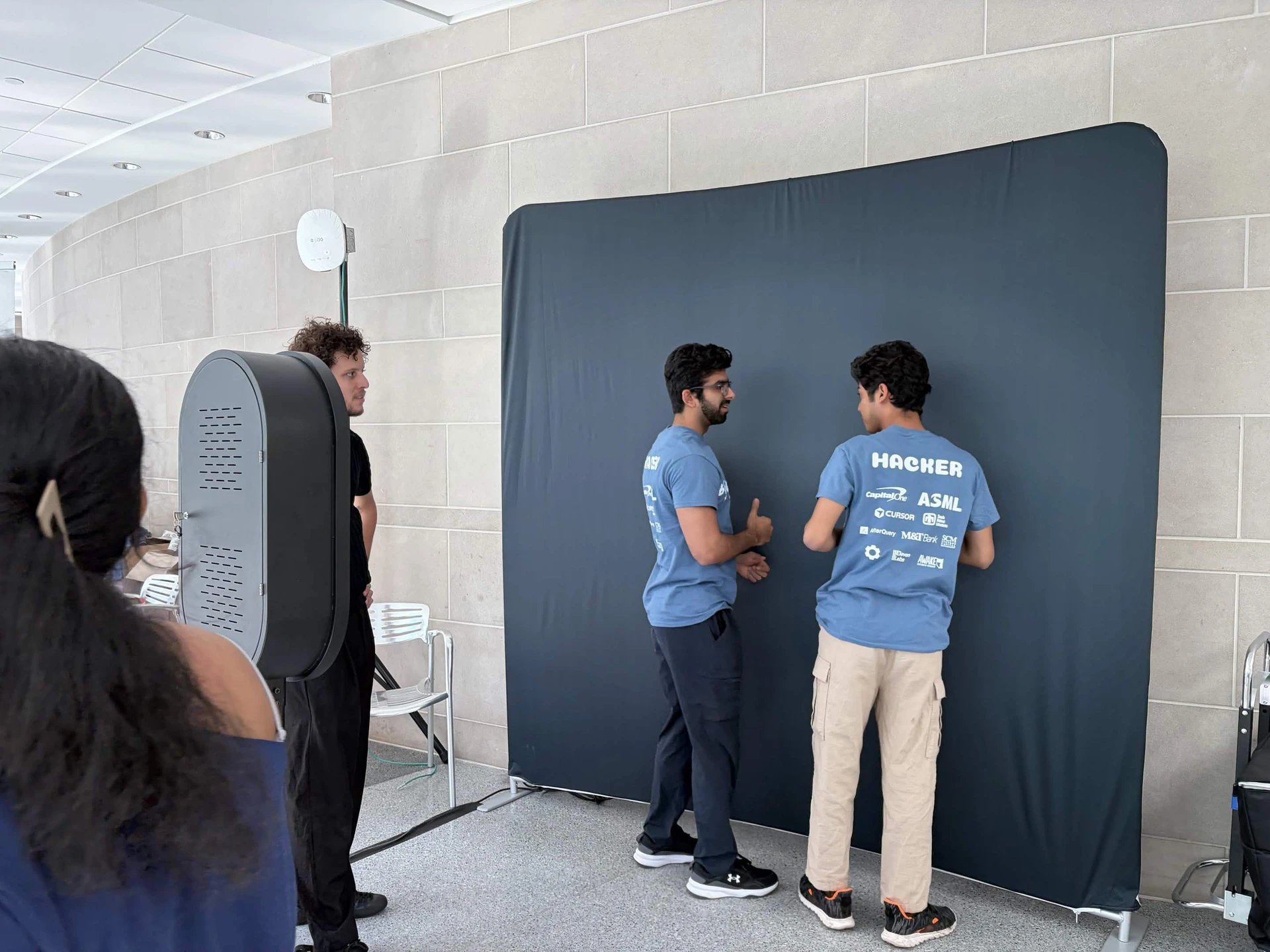 BigRed//Hacks participants at the photo booth, with HACKER lettering and sponsor logos visible on the back of a blue tee