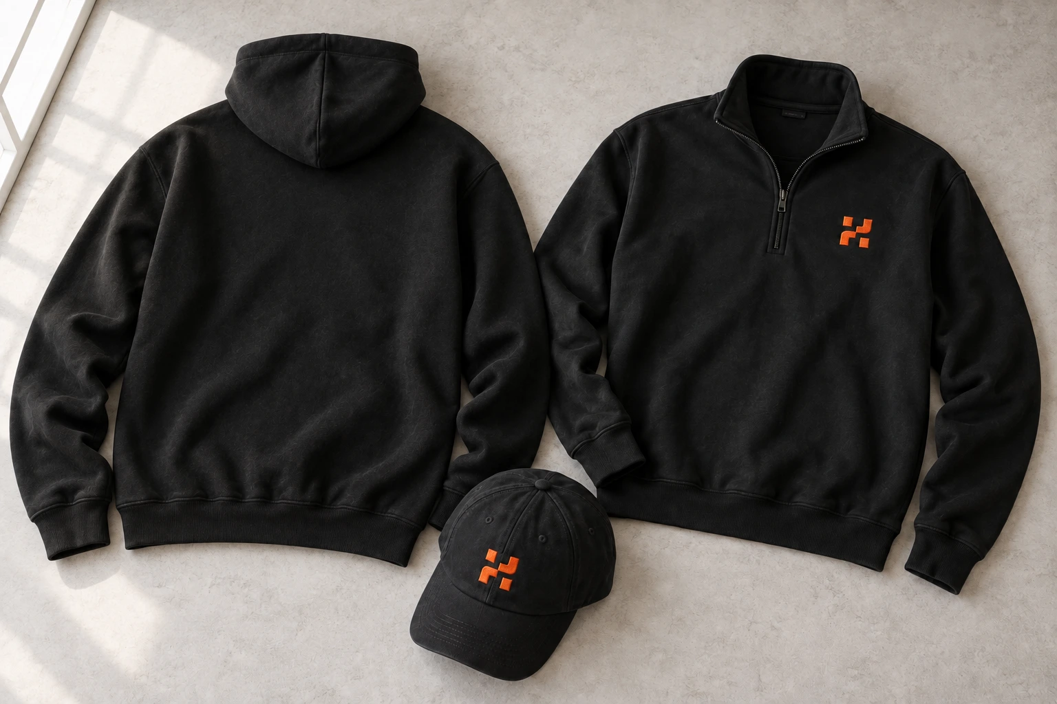 AI-generated studio visualization of a completely blank black hoodie back, a black HydraDB quarter zip with the orange symbol on the wearer's left chest, and a black cap with the symbol on the front