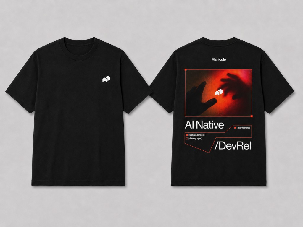 Black tee with small white manicule icon on front and AI Native DevRel back graphic with red-toned photography