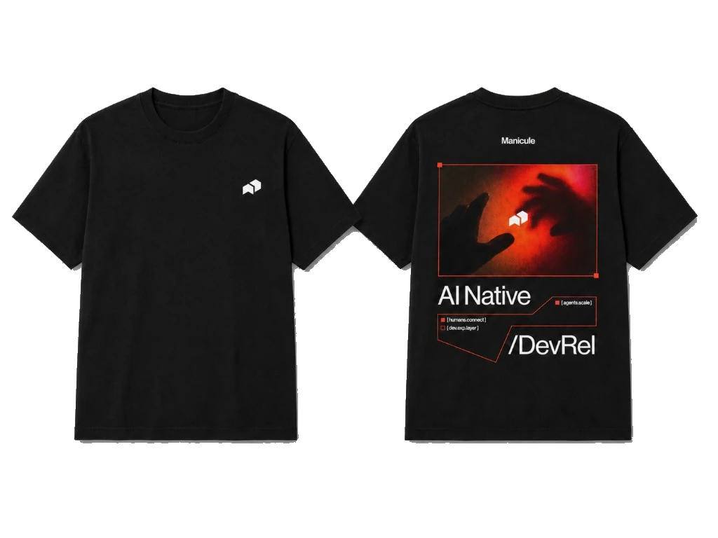 Black tee with small white manicule icon on front and AI Native DevRel back graphic with red-toned photography