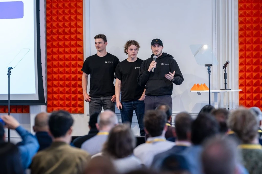 Ontora's founding team on stage at their Y Combinator batch, wearing the black Ontora tees and hoodie