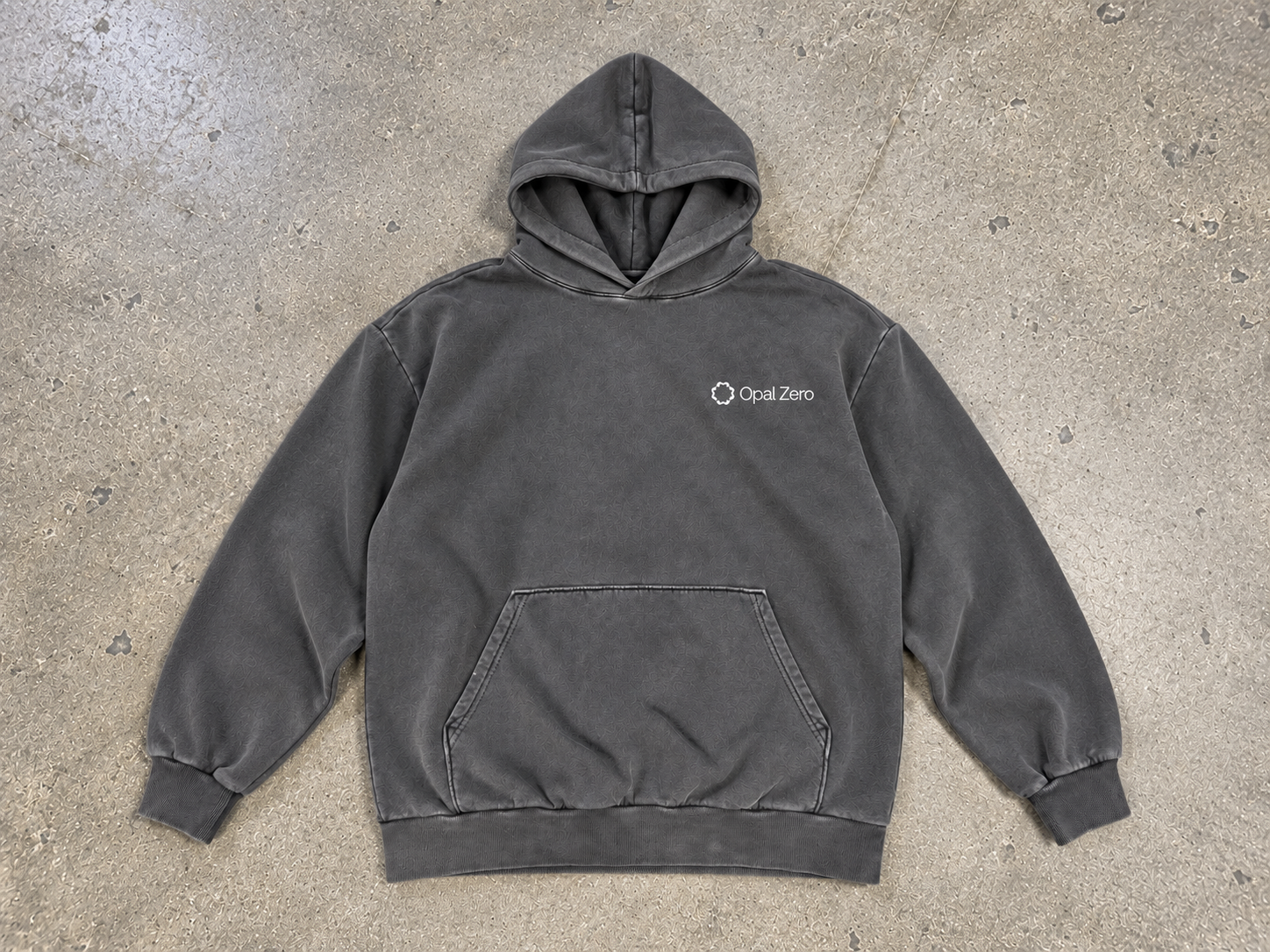 Generated photoshoot mockup of the front of a gunmetal pullover hoodie with a small white Opal Zero chest mark