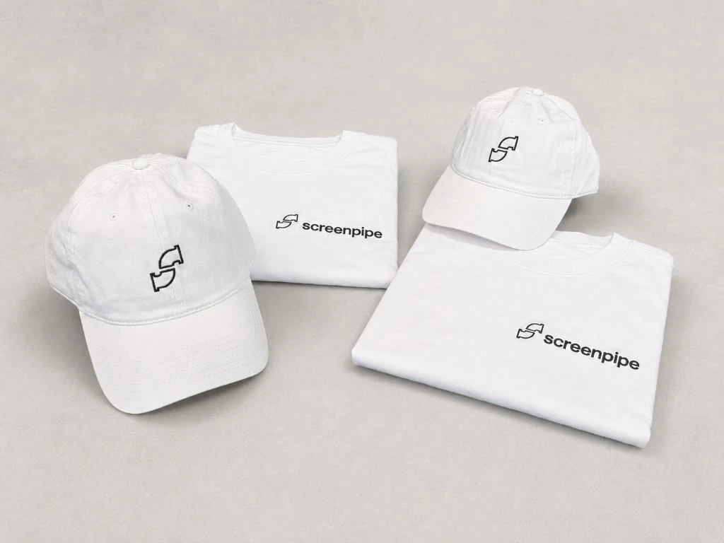 Flat-lay of white screenpipe tees with left-chest lockups and white dad caps with embroidered pipe logos